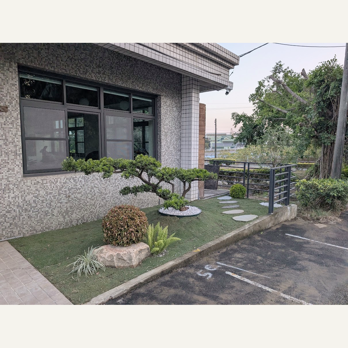 入口側面景觀,造型樹與低矮植栽旁設有踏石步道